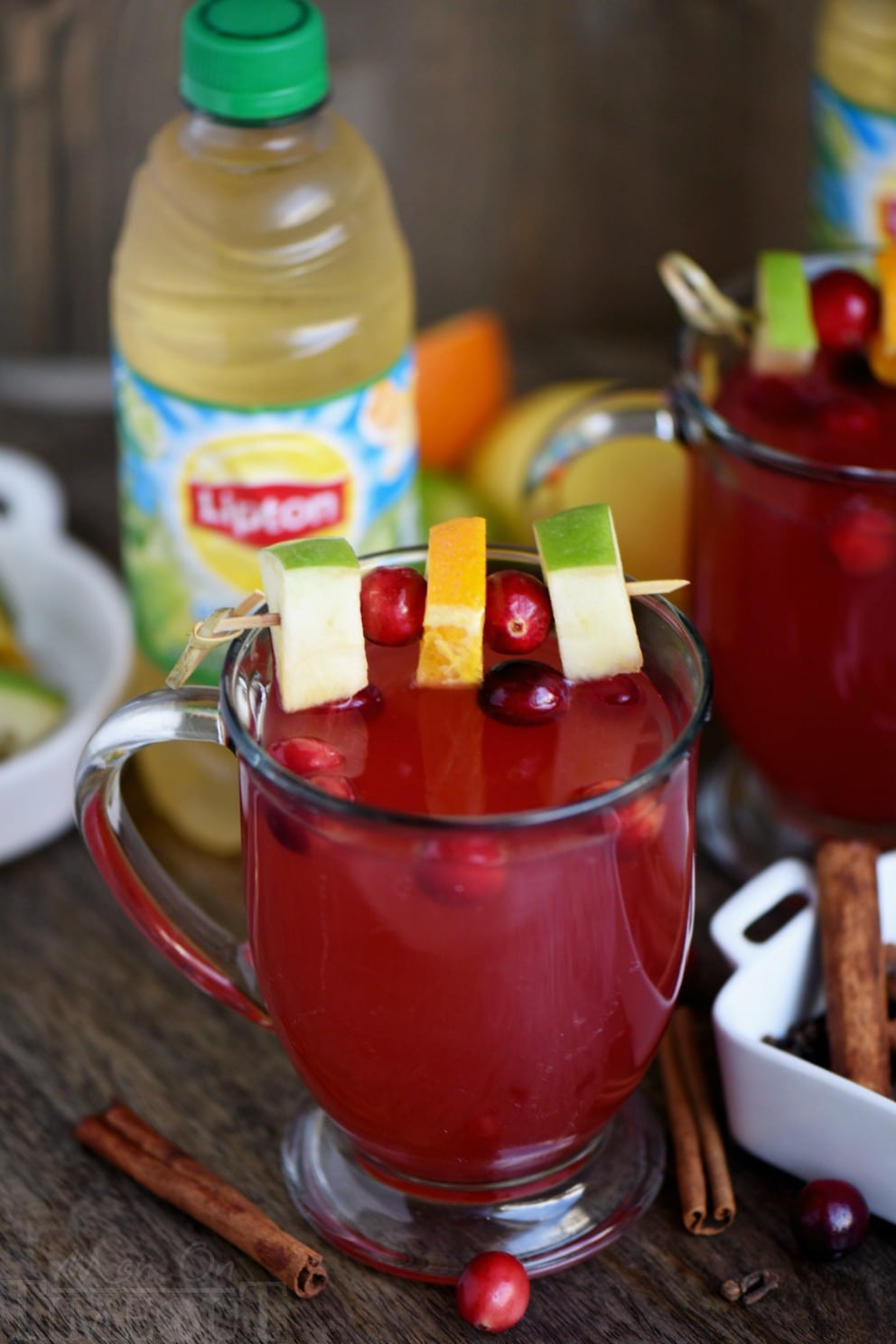 glass mug filled with cider with cinnamon sticks and cranberry around it