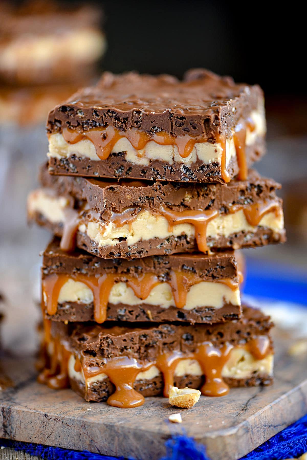 four snickers bars stacked on marble cutting board sitting on a blue napkin.