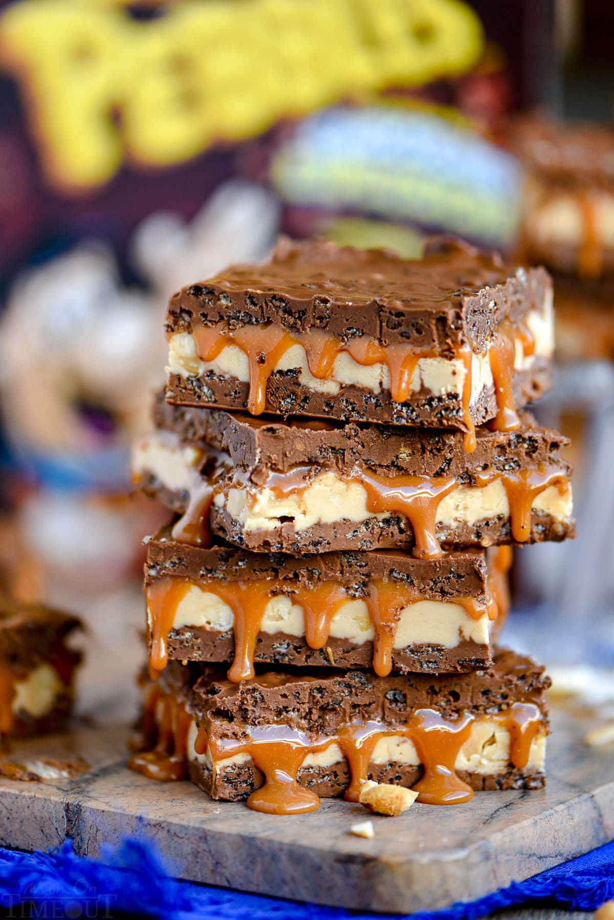 snickers bars sitting in front of a cereal box on a brown marble cutting board.