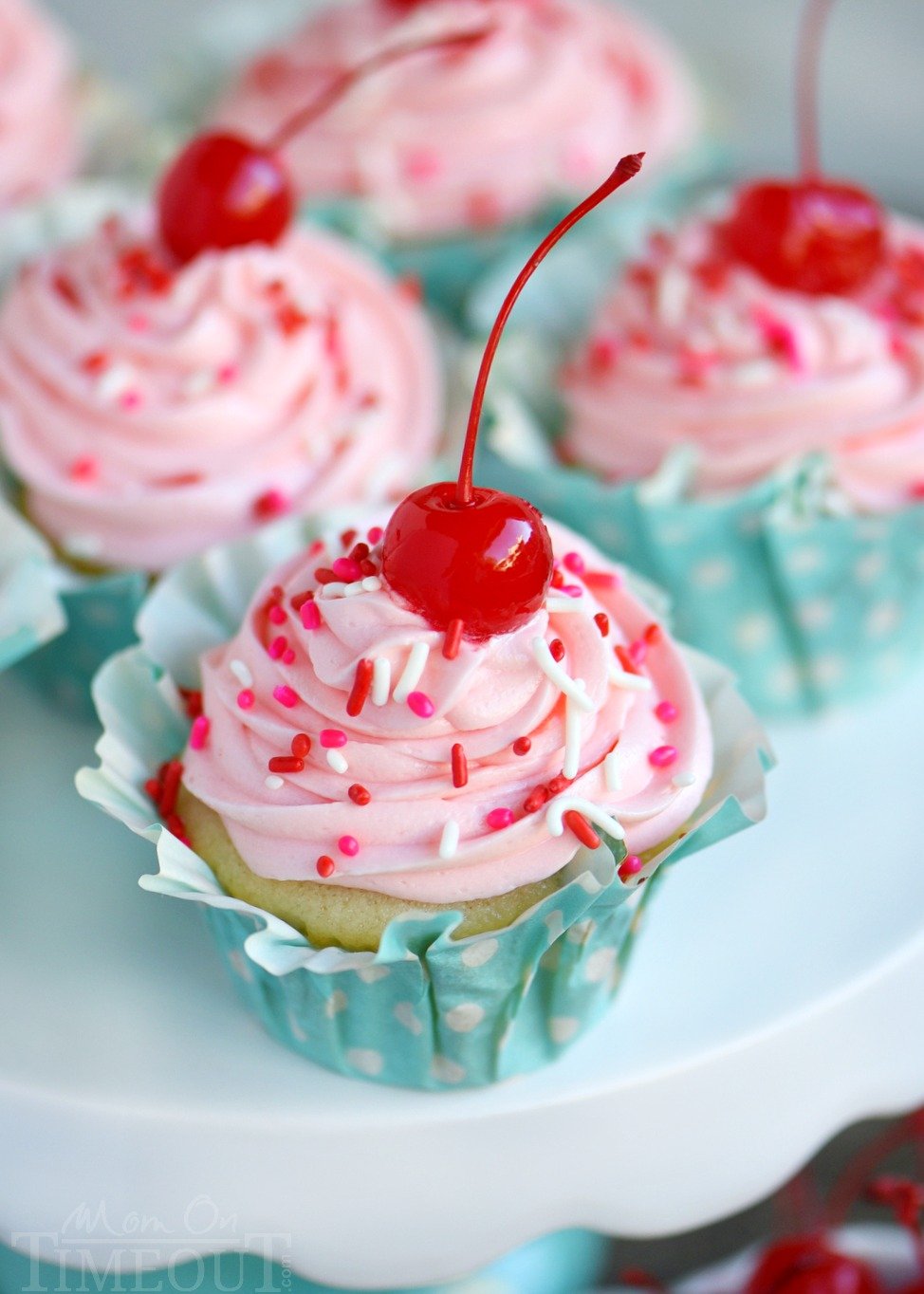 These Cherry Almond Cupcakes are so bright and festive - they're hard to resist! A beautiful almond cupcake, made from scratch, is topped with a cherry almond frosting that is just delightful! Topped with a cherry, these cupcakes are party-ready! // Mom On Timeout