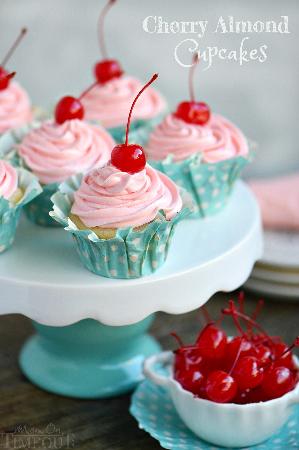 These Cherry Almond Cupcakes are so bright and festive - they're hard to resist! A beautiful almond cupcake, made from scratch, is topped with a cherry almond frosting that is just delightful! Topped with a cherry, these cupcakes are party-ready! // Mom On Timeout