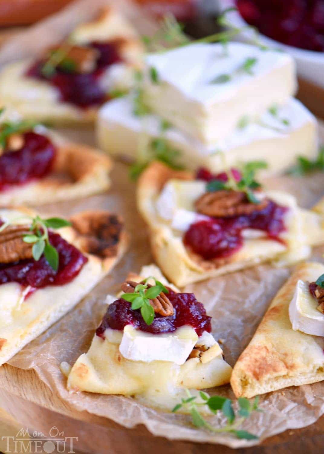 These Cranberry Pecan Brie Bites are perfect for holiday entertaining! Whether you make them for Thanksgiving, Christmas, or New Year's, no one will be able to resist the gooey melted brie, tart cranberry sauce, and toasted pecan atop a piece of naan! Easy and fabulous - just what holiday entertaining should be! // Mom On Timeout