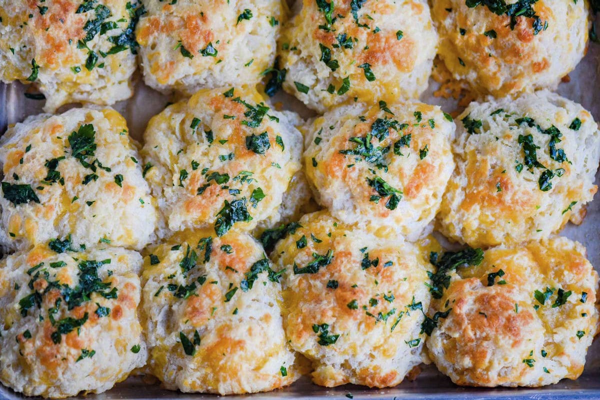biscuits topped with parsley, garlic and butter sitting on baking sheet.