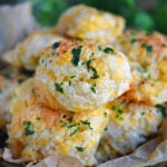 wood bowl filled with cheesy cheddar bay biscuits topped with a garlic herb butter.