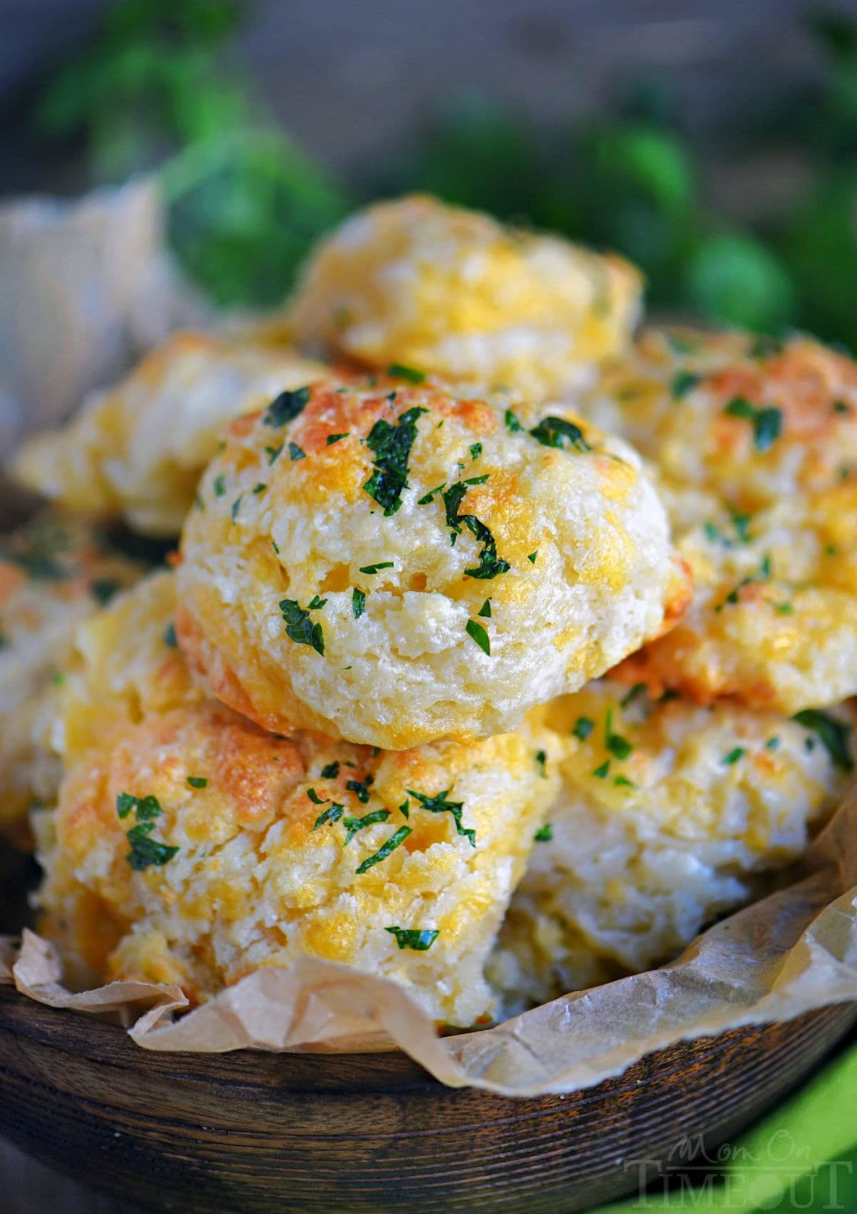 wood bowl filled with cheesy cheddar bay biscuits topped with a garlic herb butter.