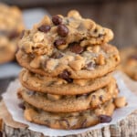 Stack of peanut butter banana chocolate chip cookies and top cookie has been torn in half.