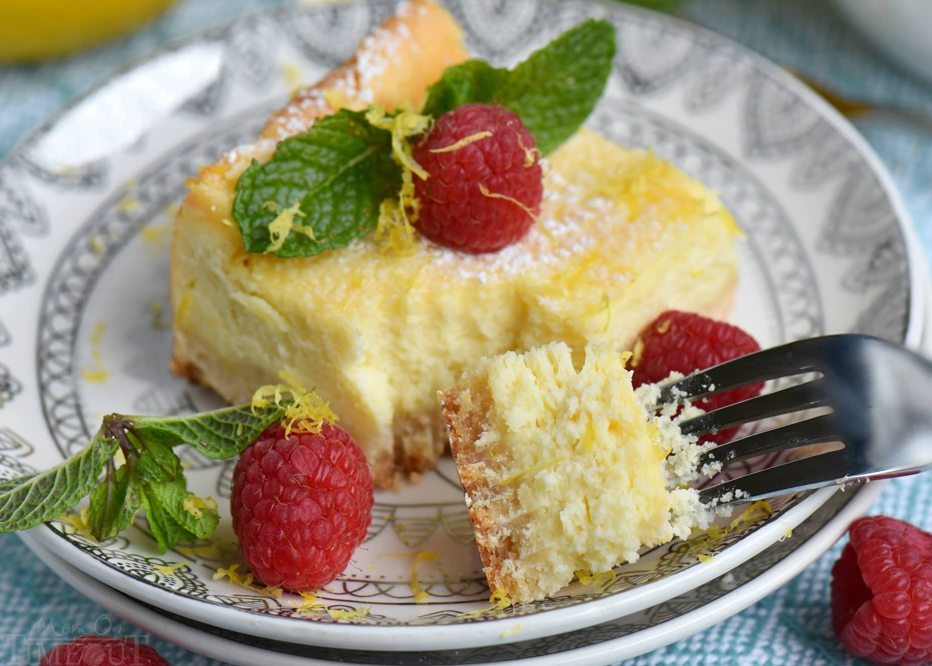 My Aunt Pam's Lemon Cheesecake Bars are made with lots of fresh lemon juice and zest so they're bursting with lemon flavor! Extra creamy, super easy and always a crowd pleaser! Top with powdered sugar, fresh raspberries, and extra lemon zest for a pretty presentation! // Mom On Timeout