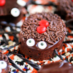black widow brownie topped with chocolate ganache, candy eyes and licorice legs sitting on a bed of halloween sprinkles.