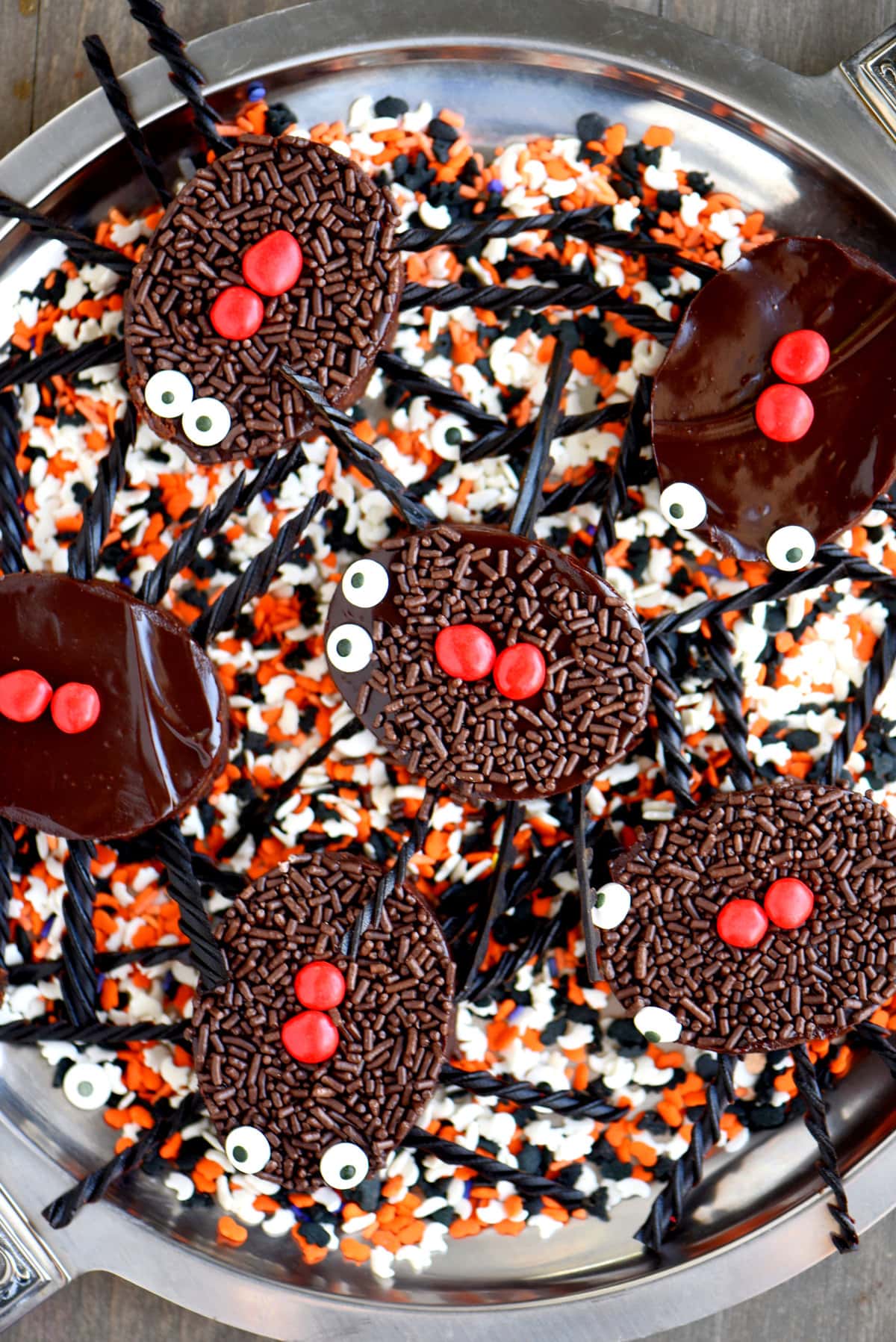 top down view of tray with brownies cut out into spider shapes sitting on colorful sprinkles.