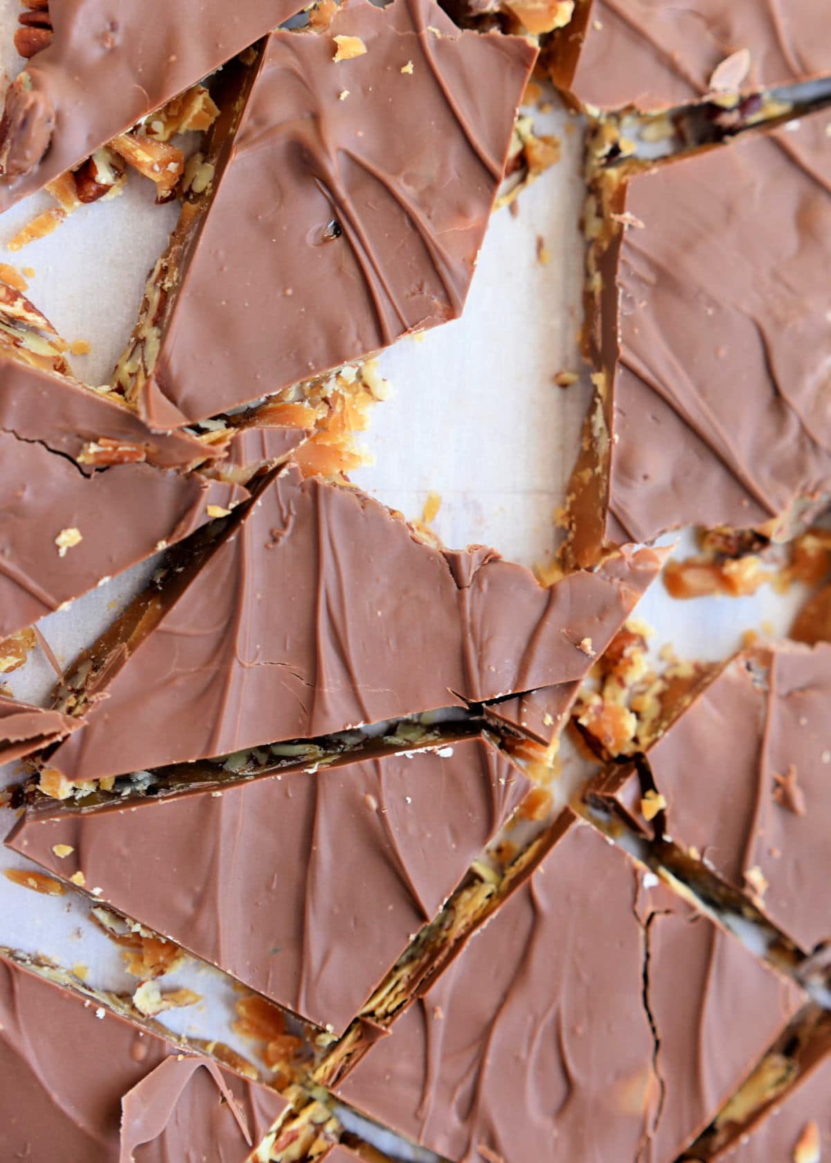 toffee candy broken up on a piece of parchment paper into smaller pieces.