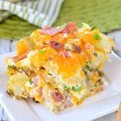 a generous serving of twice baked potato casserole sitting on a small white square plate with casserole dish in back ground.