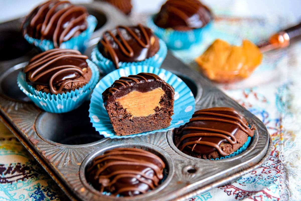 half of a buckeye bite sitting with other cookies on a vintage mini muffin pan.