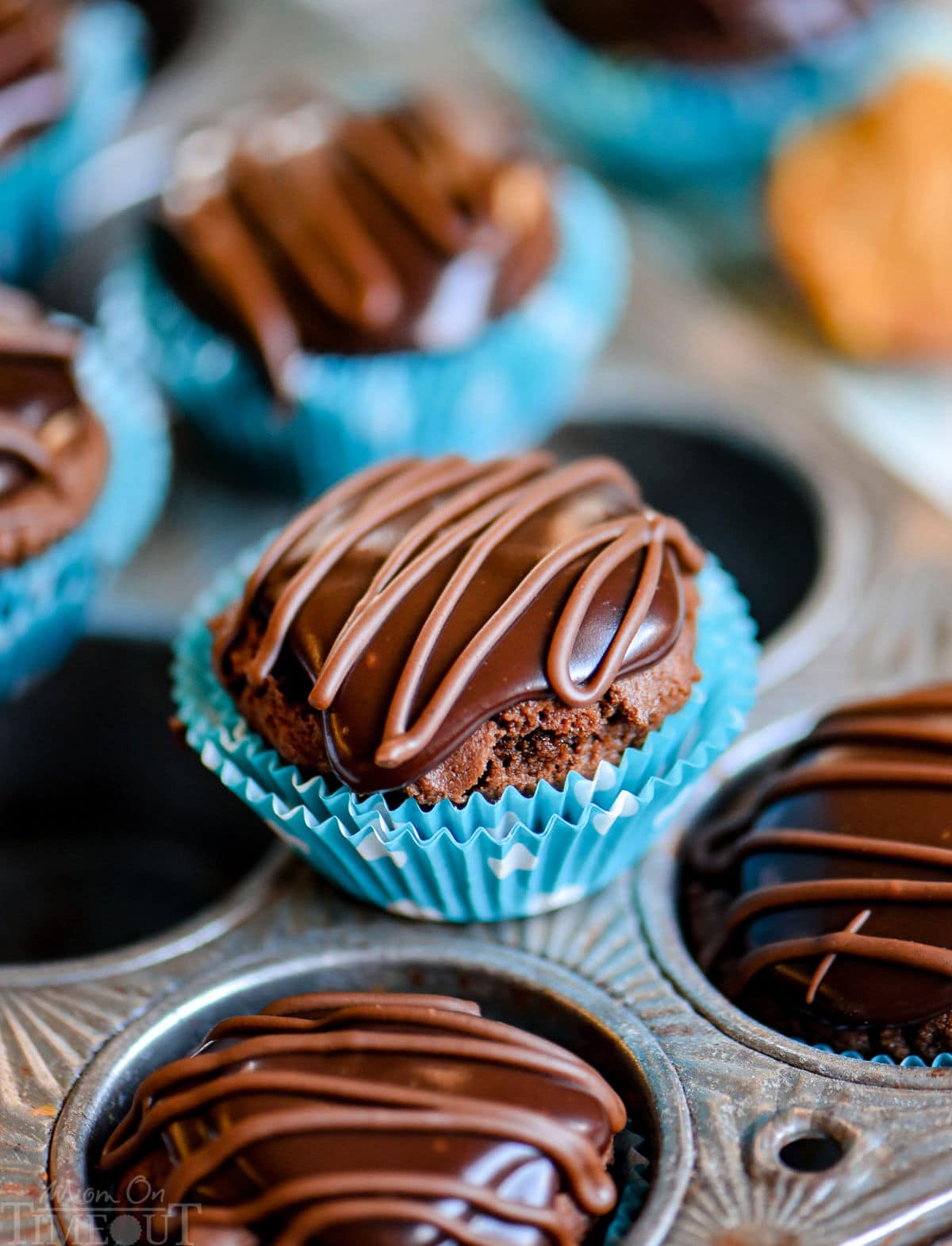 one buckeye bite in polka dot blue and white mini muffin liner on top of muffin pan near other treats.