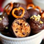 white bowl filled with peanut butter balls and the one in the front has a bite out of it.