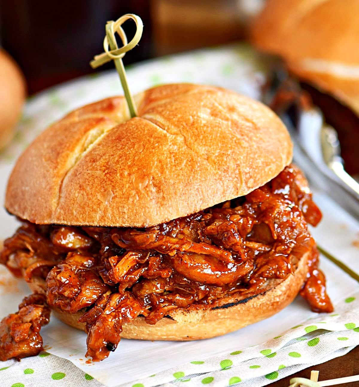 bbq pulled chicken recipe on a toasted bun with a toothpick through the top bun.
