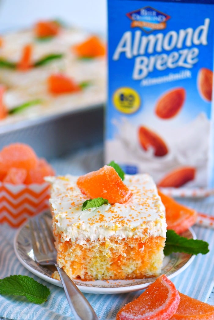 orange creamsicle cake with mint leaves on small plate with fork with candied oranges and mint leaves on piece of cake