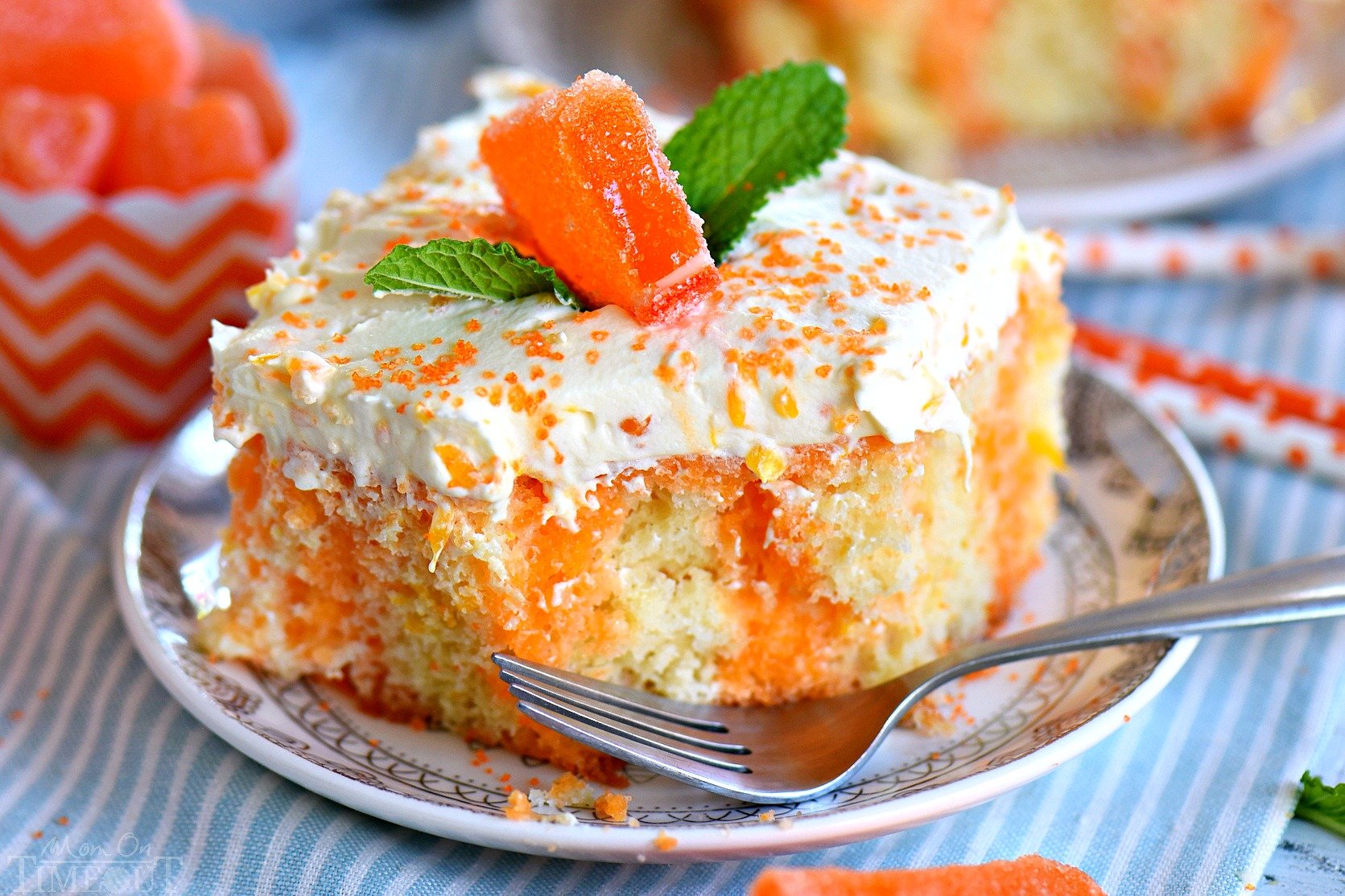 square of orange cake on small white plate with bite taken