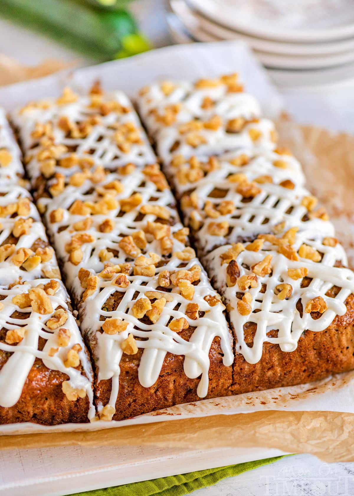 Zucchini snack cake cut into nine squares sitting on parchment and white board.