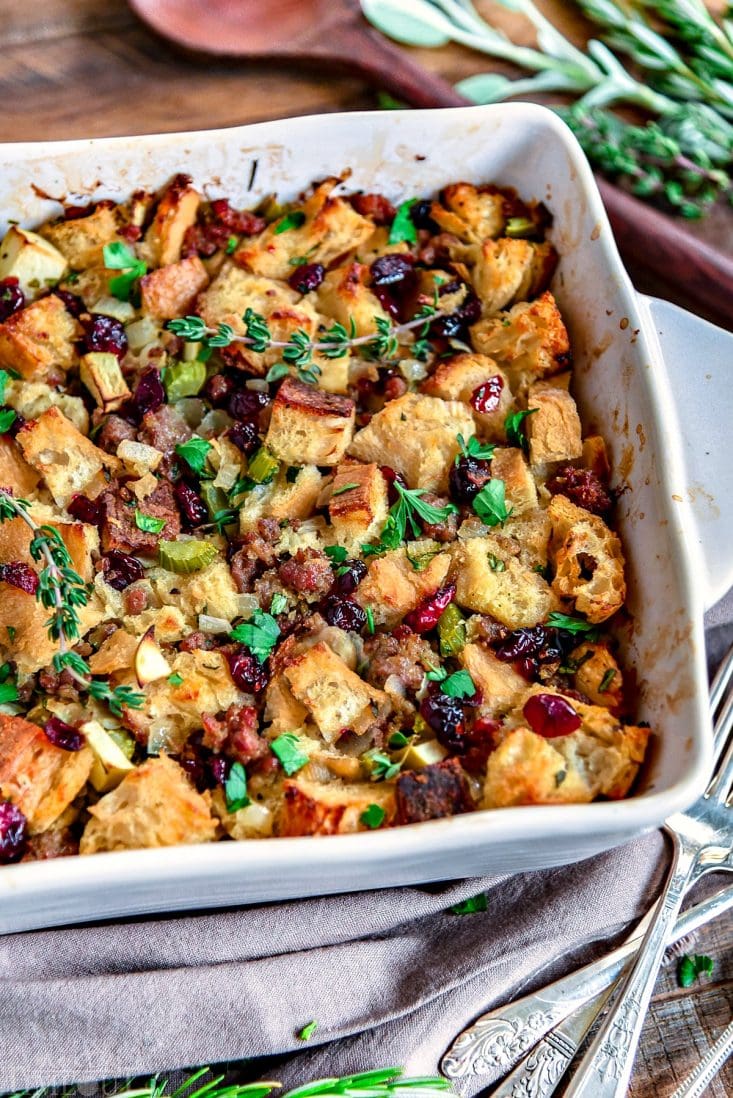 This easy Sausage Stuffing Recipe is our absolute favorite! Loaded with sausage, cranberries, apples and tons of fresh herbs it's the perfect addition to your holiday feast! // Mom On Timeout #sausagestuffing #stuffingrecipe #Thanksgiving #christmas #stuffing #recipe #dressing #sausage #cranberries #apple #sage #recipes #holidays