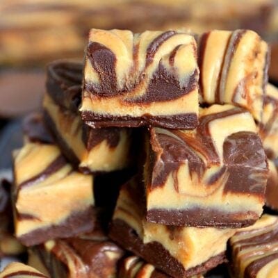 pieces of peanut butter cup fudge cut into squares and stacked high showing the swirls in the top of the fudge.