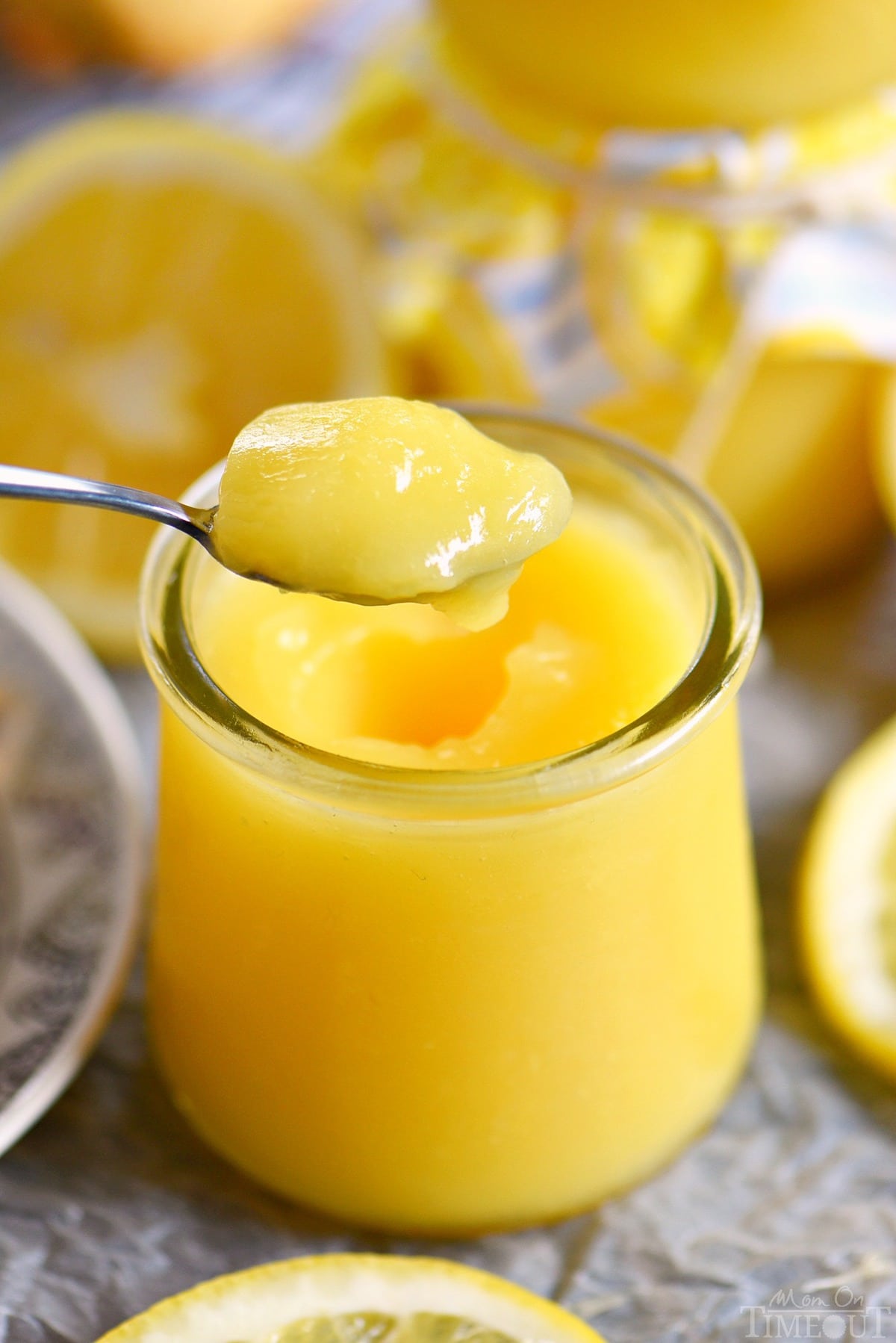 spoonful of lemon curd and a glass jar filled with lemon curd