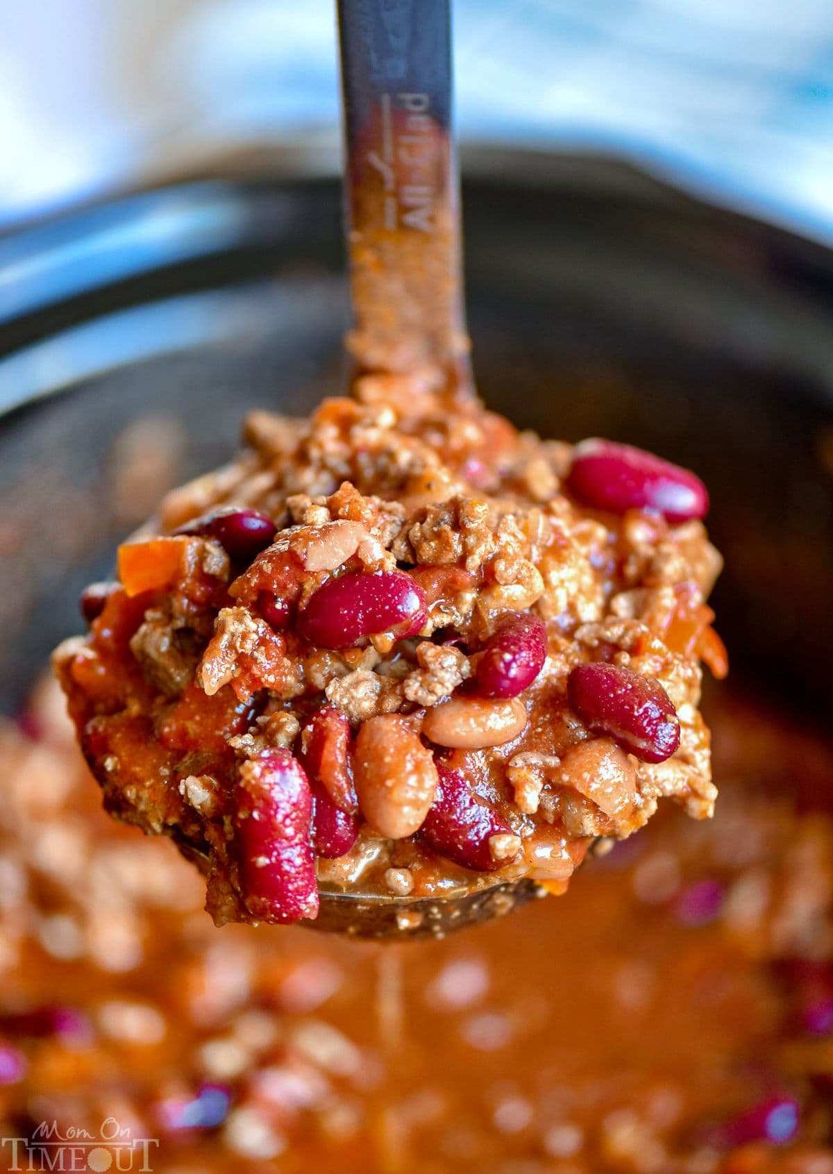 crockpot chili in a ladle held above the crockpot and the rest of the chili.