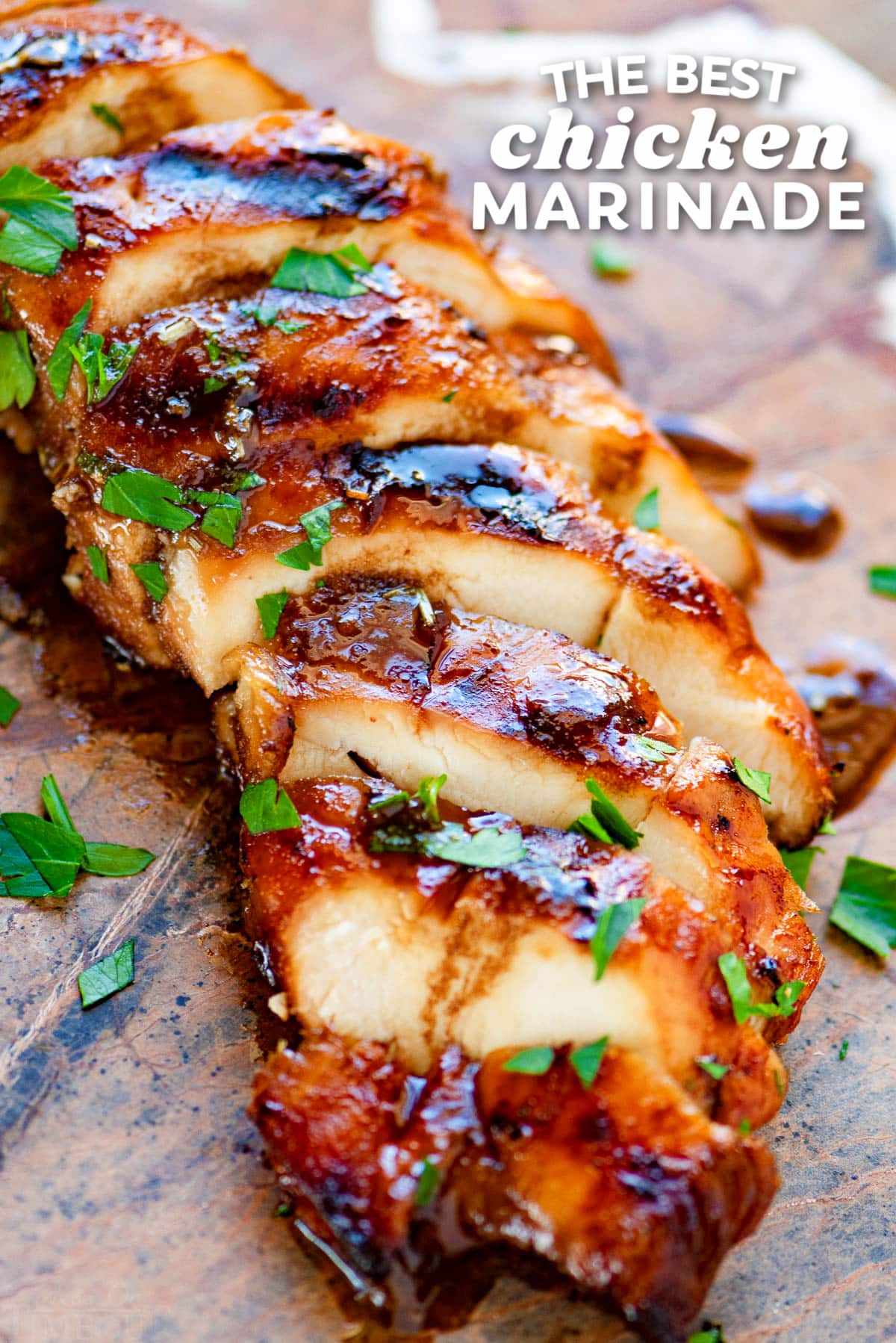 grilled chicken breast made with chicken marinade sliced on stone cutting board with title overlay at top of image.