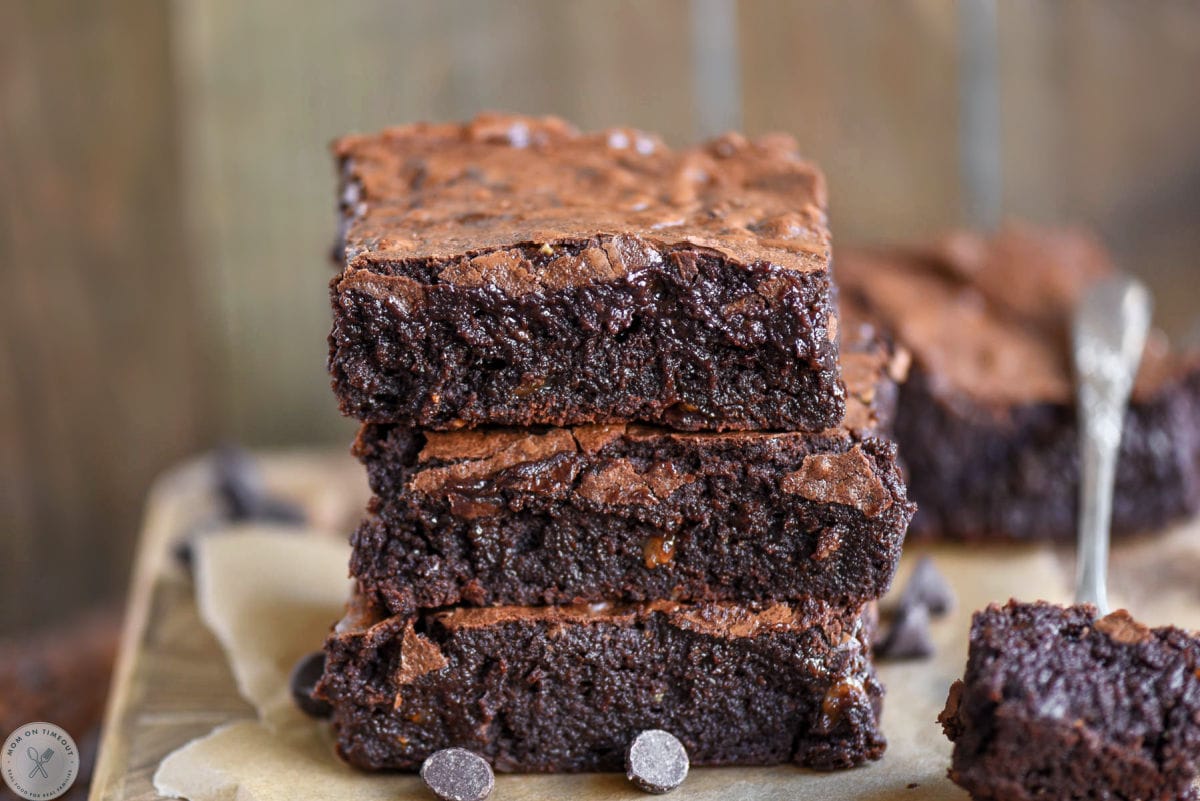 Wide shot of brownies stacked three high with a bite of a brownie on a fork next to the stack.
