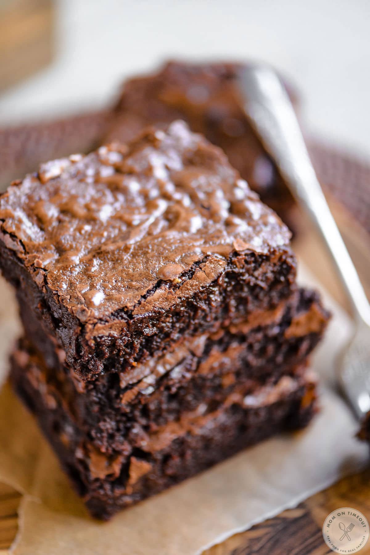 Overhead angled shot of stack of brownies on brown parchment.