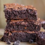 Shot of brownies stacked three high with a bite of a brownie on a fork next to the stack.