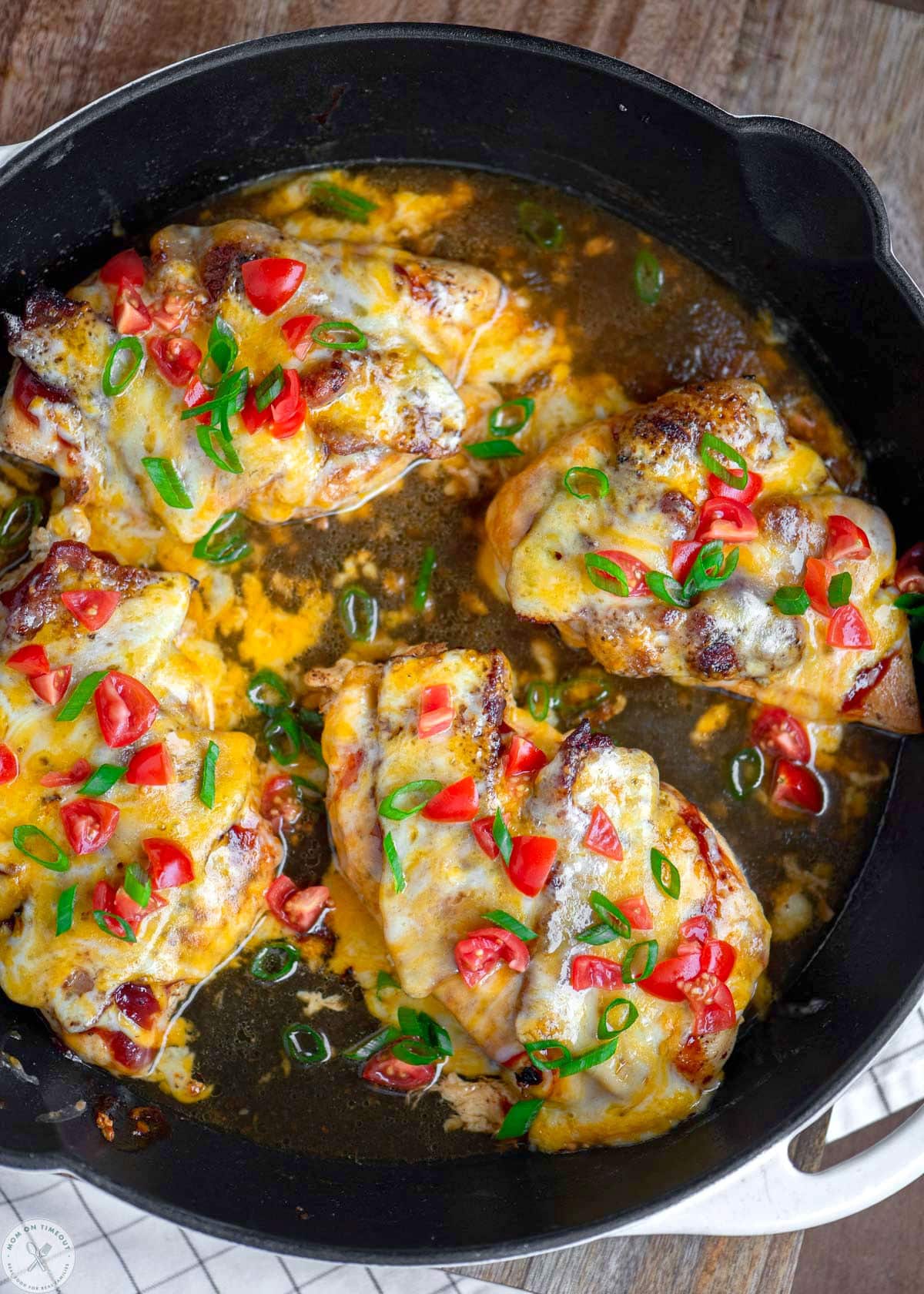 Pulled back overhead shot of four chicken monterey in a skillet ready to be served. 