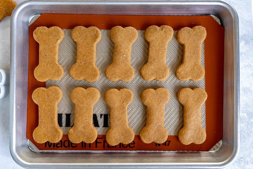 These Homemade Dog Treats are made with peanut butter and pumpkin and are sure to be a hit! This easy recipe is made in one bowl with just 5 ingredients - simple and delicious! // Mom On Timeout #dogtreats #homemadedogtreats #pumpkin #peanutbutter #dogs #dog #peanutbutterdogtreats #pumpkindogtreats #ad homemade dog treats cut out on baking sheet unbaked