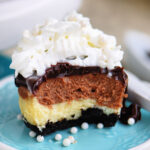 mini cheesecake split in half to show chocolate and vanilla marbled layers. topped with ganache and whipped cream and sitting on a small green plate.