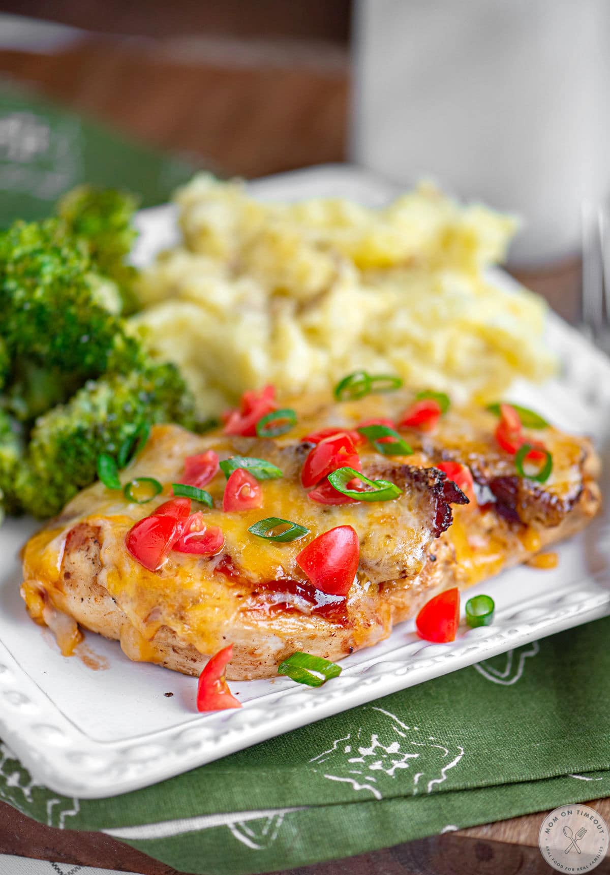 Monterey chicken recipe on white square plate with mashed potatoes and broccoli.