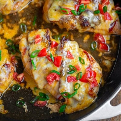 Overhead shot of monterey chicken recipe prepared in skillet and topped with green onions and bright red tomatoes. Ready to serve.