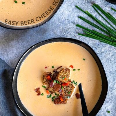 beer cheese soup recipe in black bowls with croutons bacon and chives text