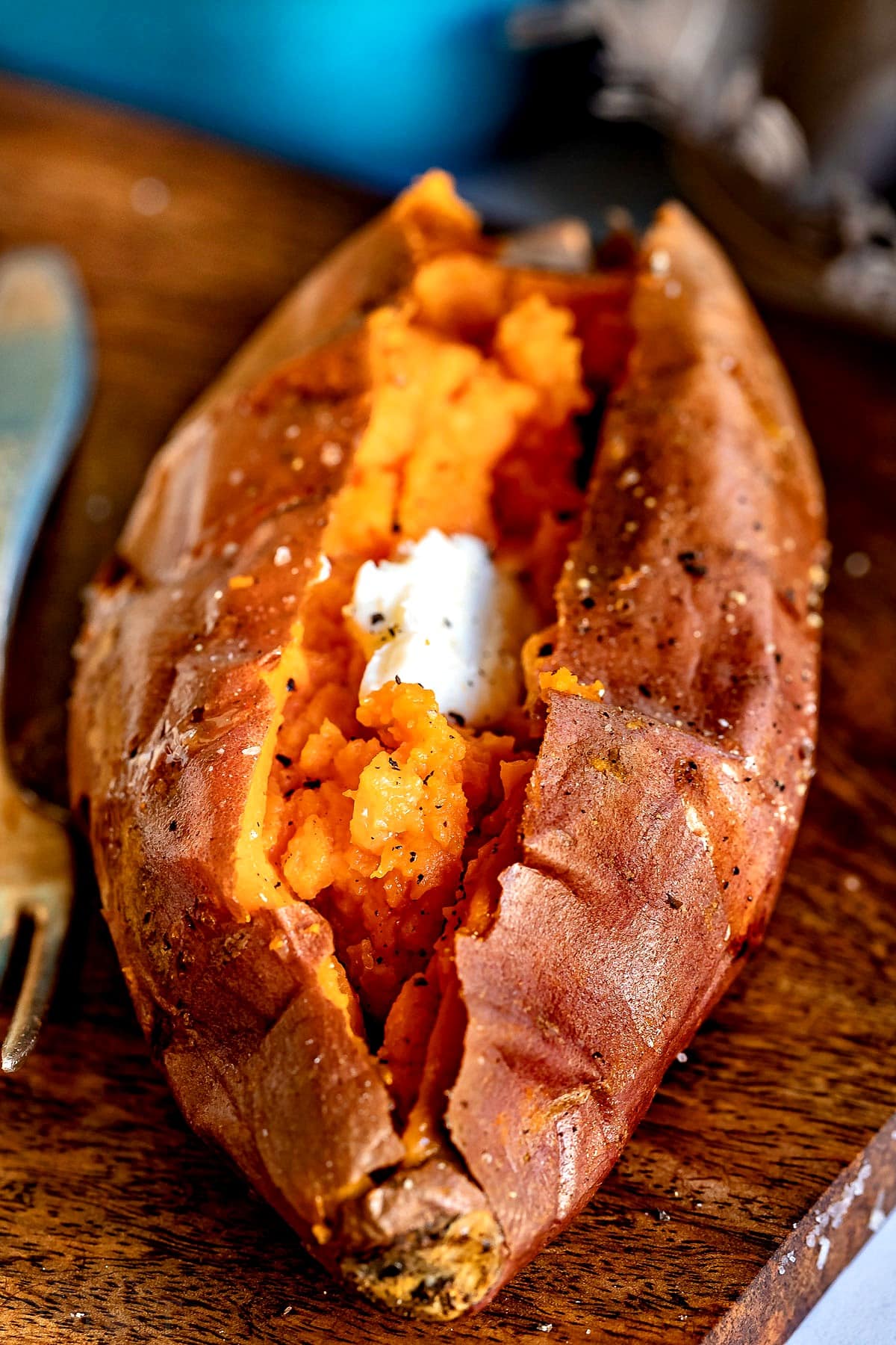 Large baked sweet potato on wood cutting board.