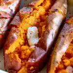 Close up of baked sweet potato cut in half and topped with butter.
