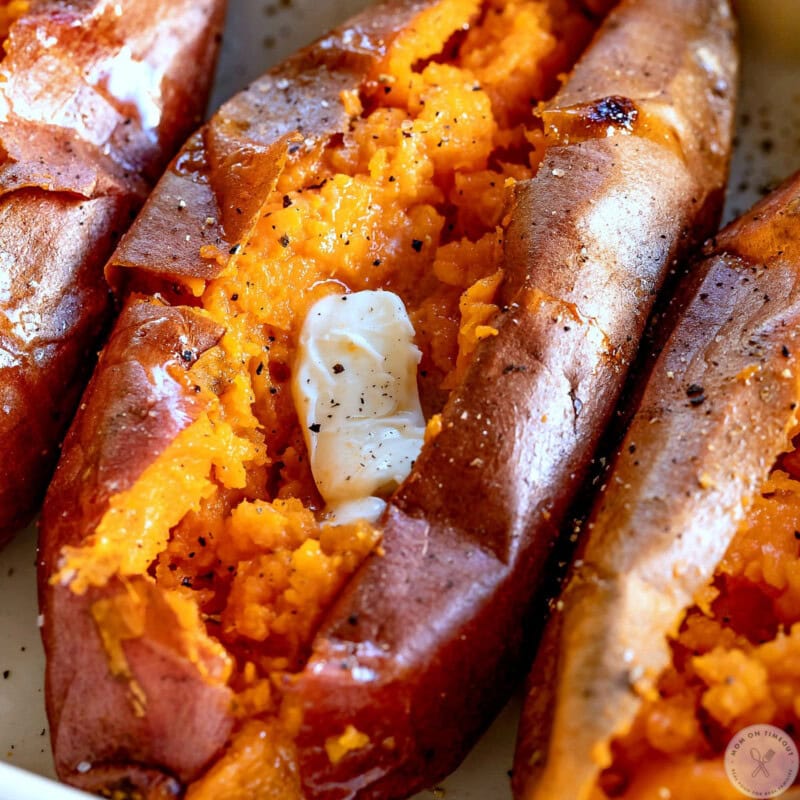 Close up of baked sweet potato cut in half and topped with butter.