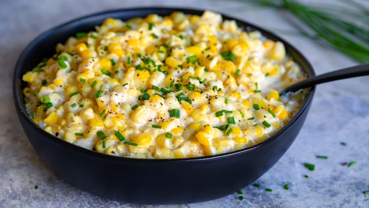 cream style corn recipe in serving bowl with chives