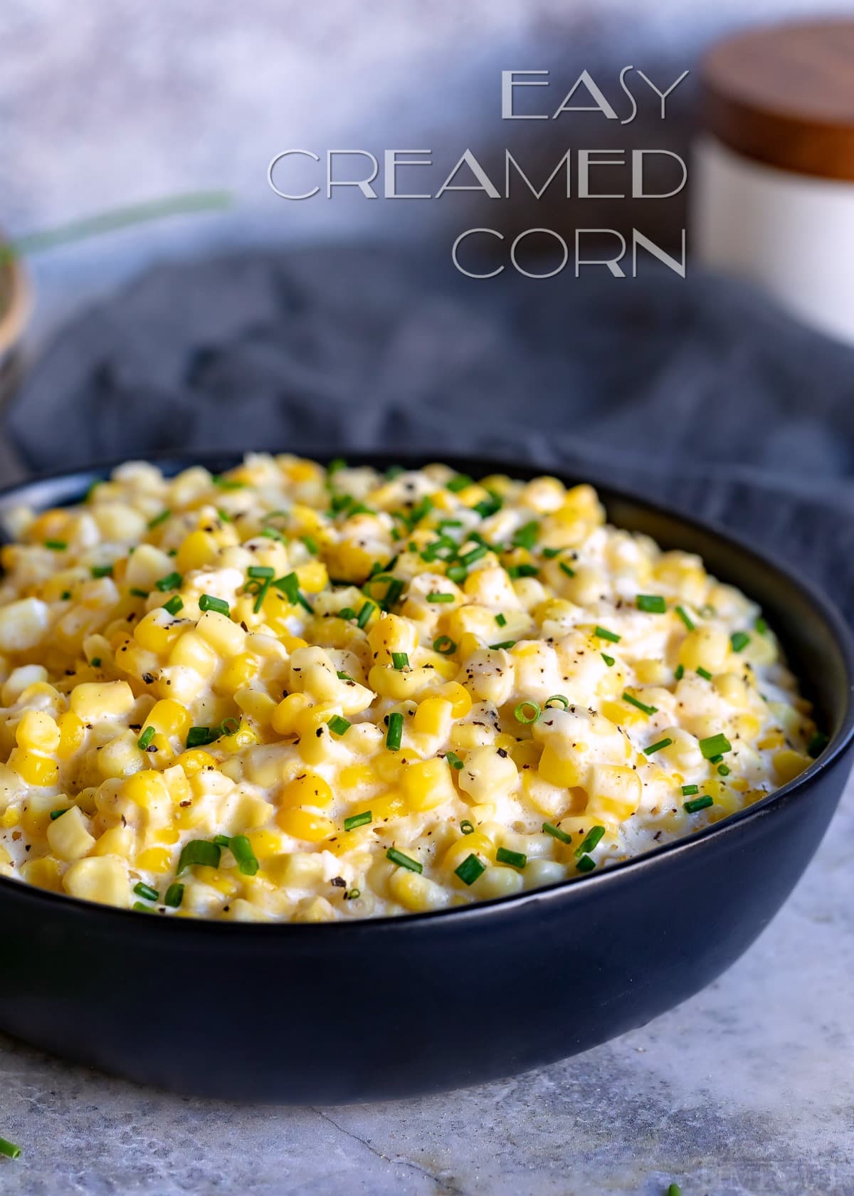 creamed corn in black bowl with chives garnish