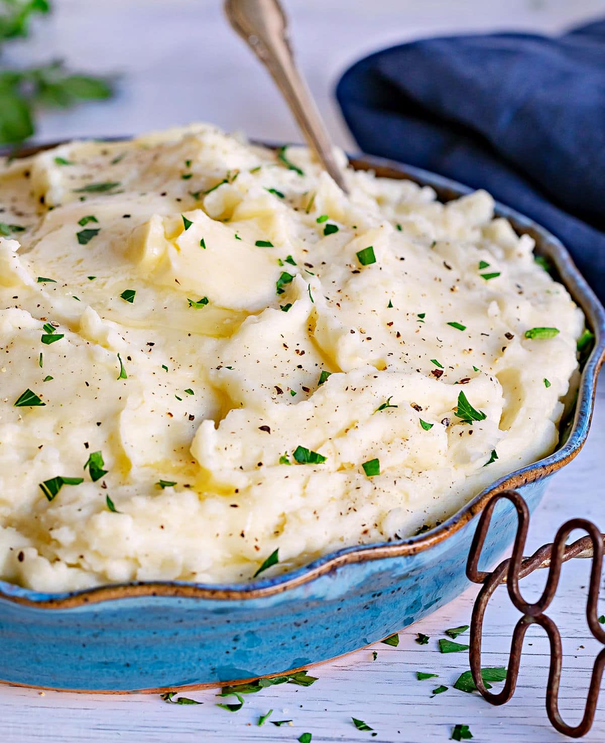 easy mashed potatoes recipe topped with butter in a blue serving bowl