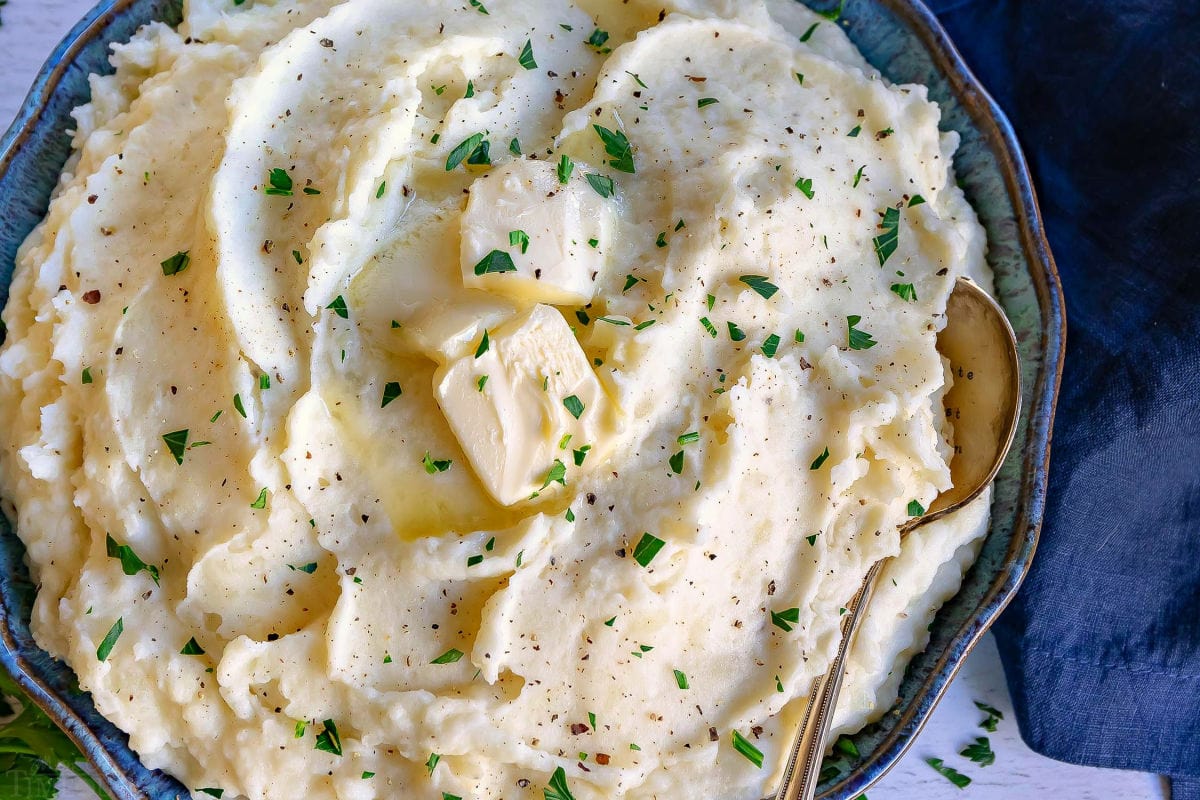 mashed potatoes close up with butter and parsley on top