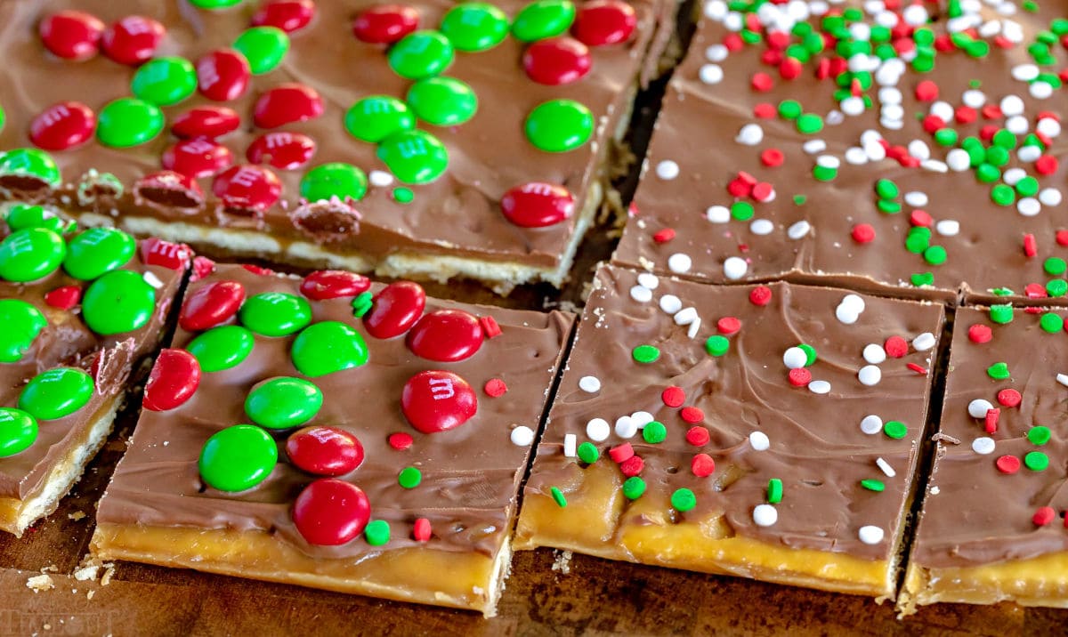 large sheet of saltine toffee cut into squares on wood cutting board ready to be served.