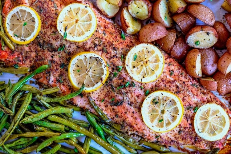 Easy Baked Salmon is healthy, delicious, and FAST! Fresh salmon is topped with a simple honey dijon glaze and baked to perfection. Prepped and cooked in under 30 minutes! // Mom On Timeout #bakedsalmon #salmon #salmonrecipe #easysalmonrecipe #easy #sheetpan #dinner #dinners #30minutemeals #veggies baked salmon recipe on a sheet pan with green beans potatoes and lemons