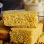 homemade cornbread stacked on a dark cutting board served with honey and butter pinterest image