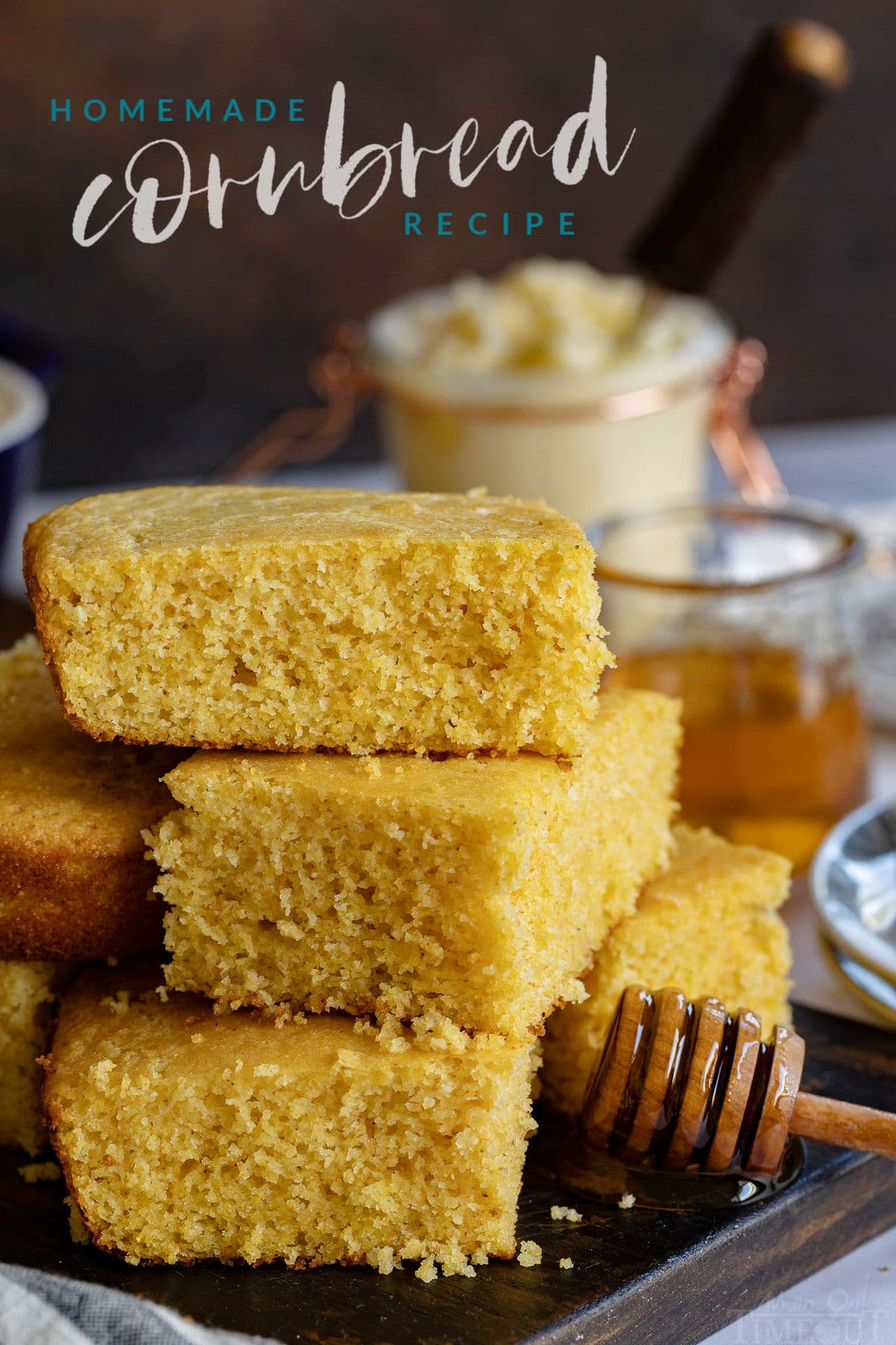 homemade cornbread stacked on a dark cutting board served with honey and butter