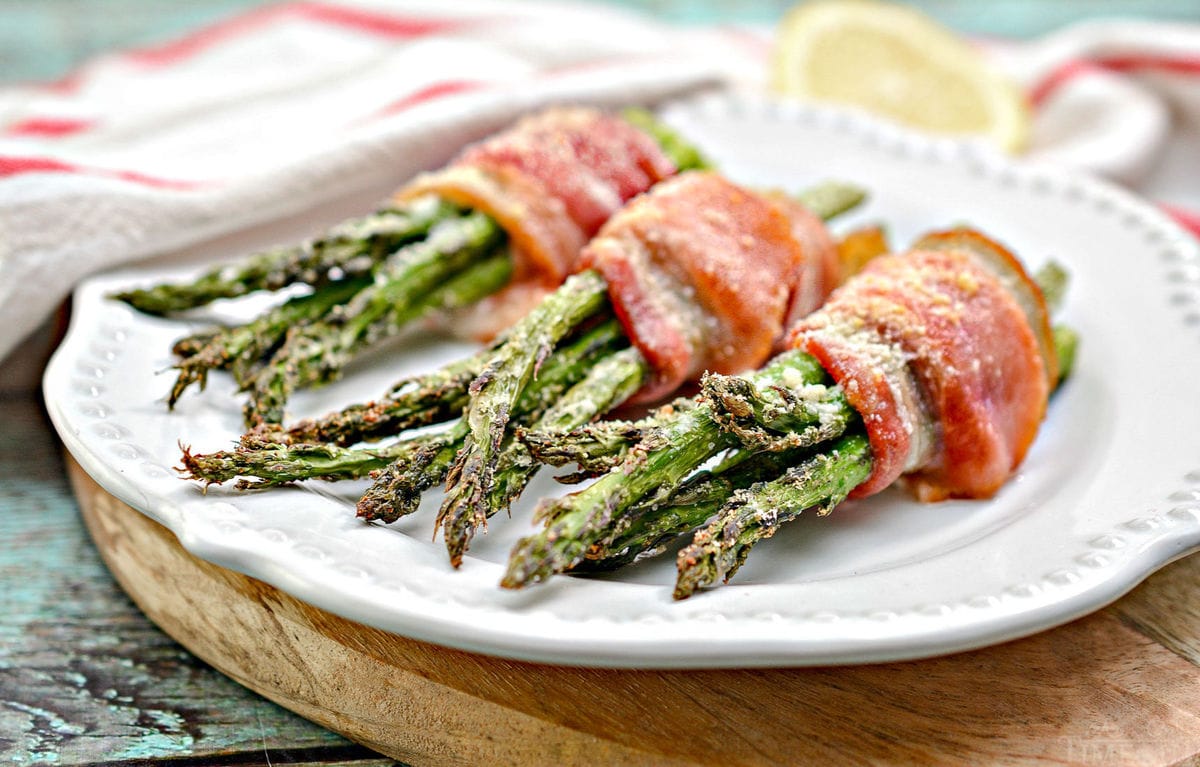 bacon wrapped asparagus recipe on white plate on cutting board