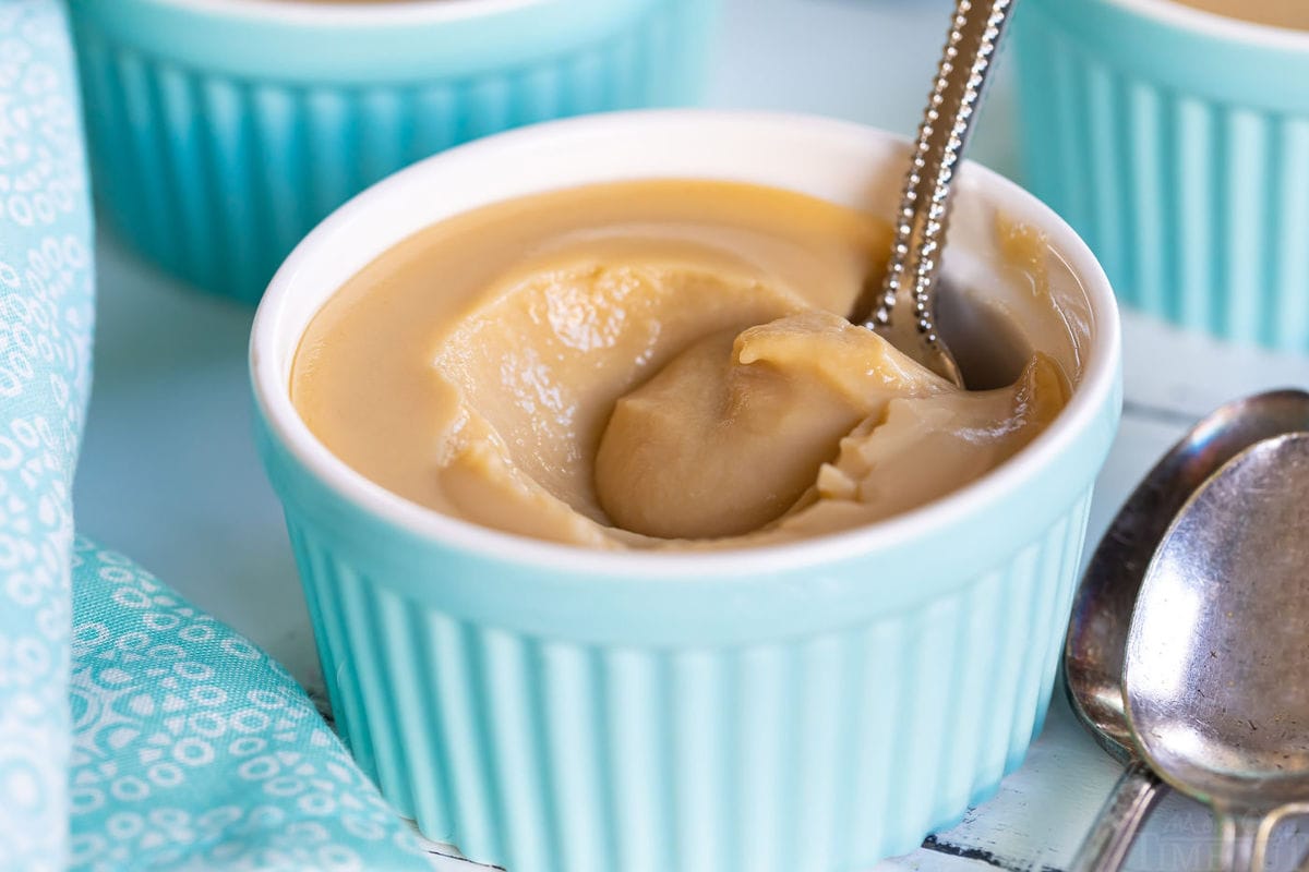 homemade butterscotch pudding in a ramekin half eaten with antique spoon