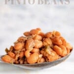 pinto beans recipe in a serving spoon with white crockpot with text overlay